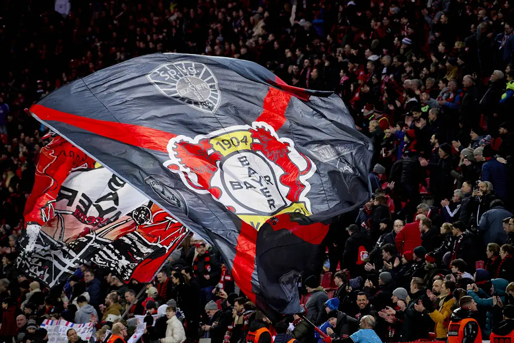 Supporters du Bayer Leverkusen dans les tribunes pendant un match avec un énorme drapeau