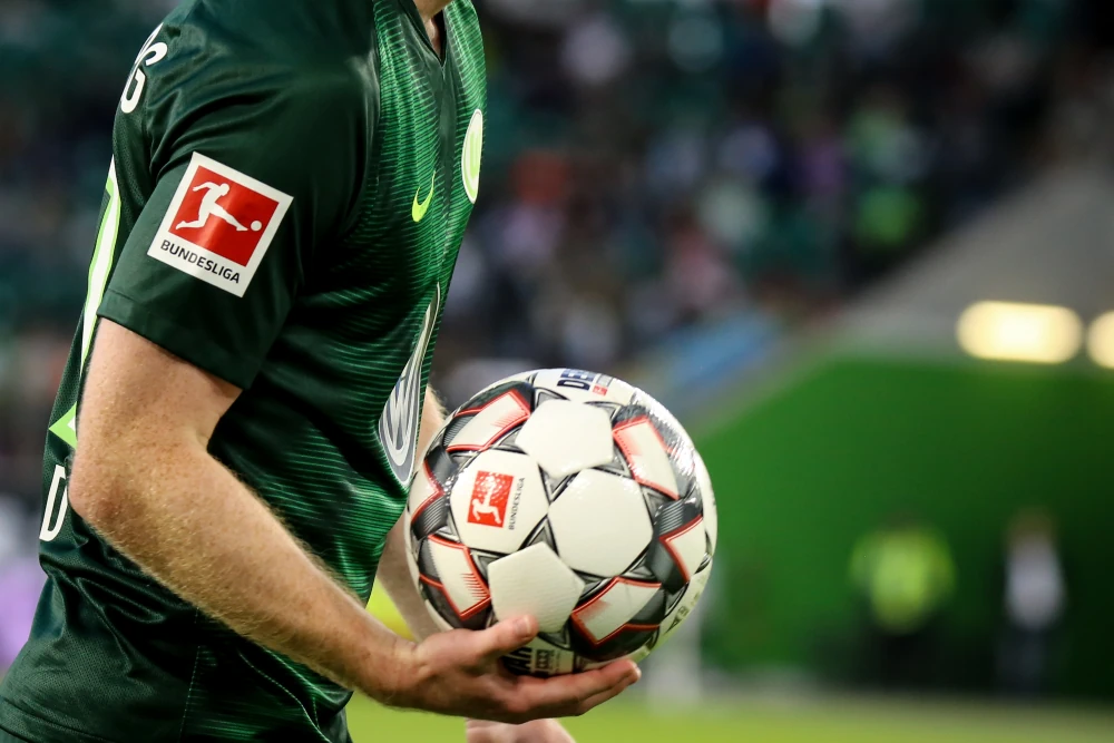 Logo de la Bundesliga sur le maillot d'un joueur et le ballon dans ses mains